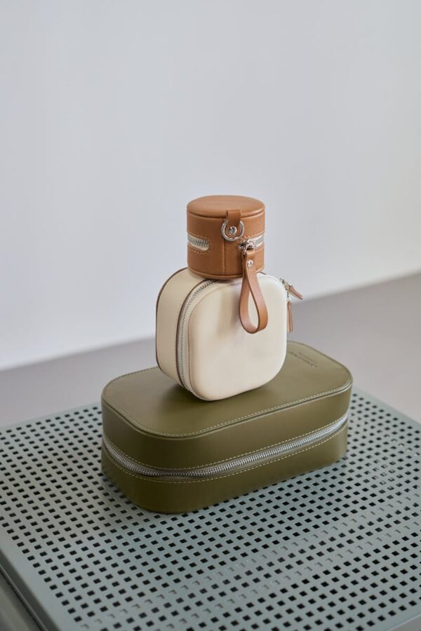 Stylish designer handbags stacked on a perforated surface in a minimalist studio setup.